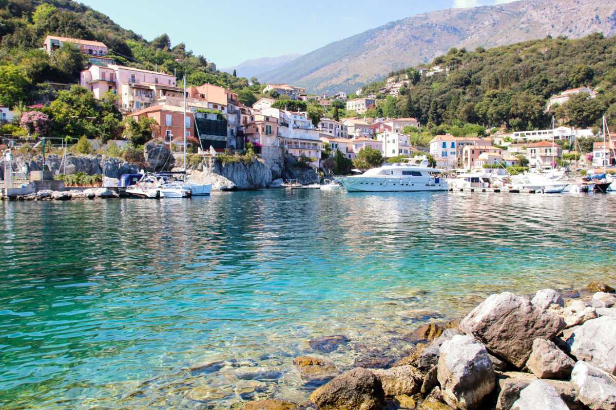 Vista panoramica sul Porto Turistico di Maratea al tramonto con barche attraccate, locali illuminati e la costa